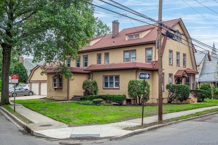 View of front of house featuring a chimney, stucco siding, a front lawn, and a garage