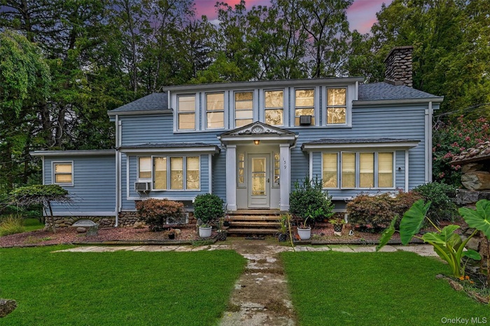 Traditional-style home with a chimney, a yard, and a shingled roof