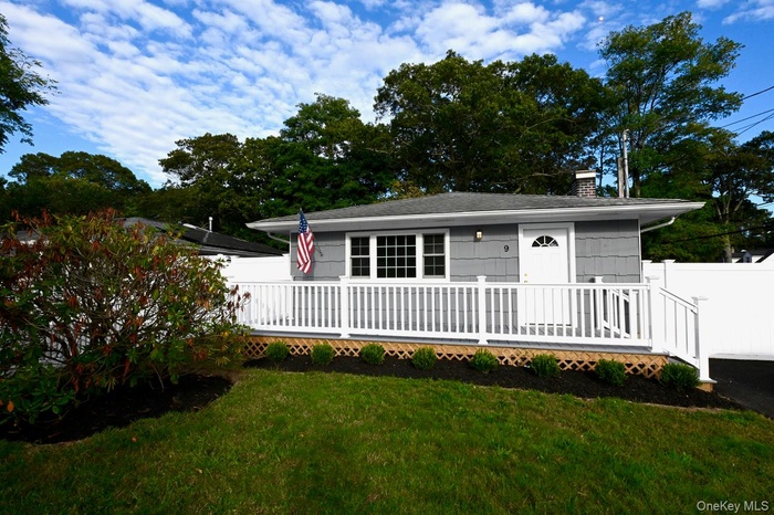 View of front facade with a front lawn, a chimney, and a wooden deck