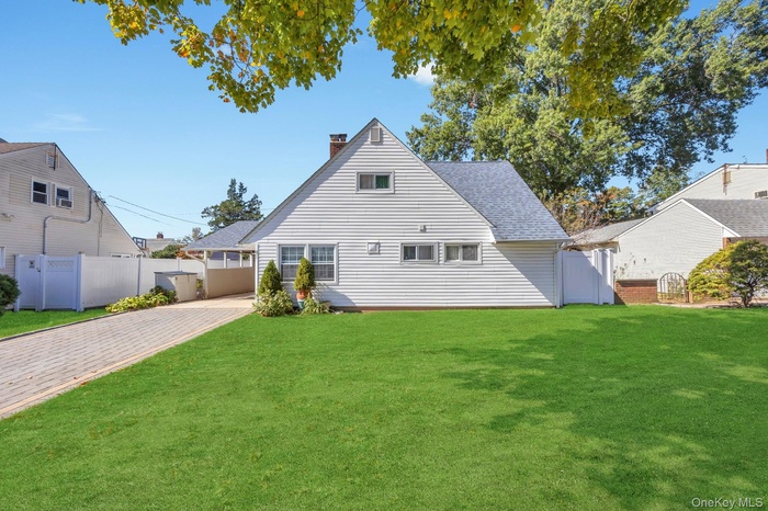 Back of house featuring a chimney, roof with shingles, and a gate