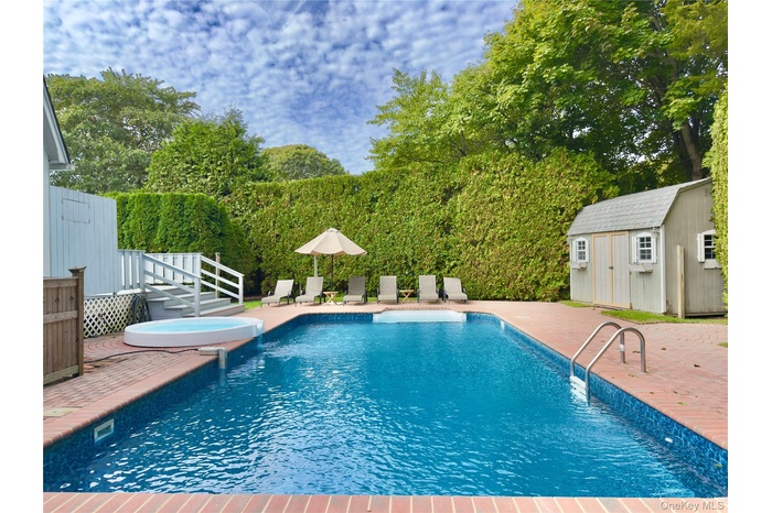 View of swimming pool with a patio, a storage shed, a pool with connected hot tub, and a wooden deck