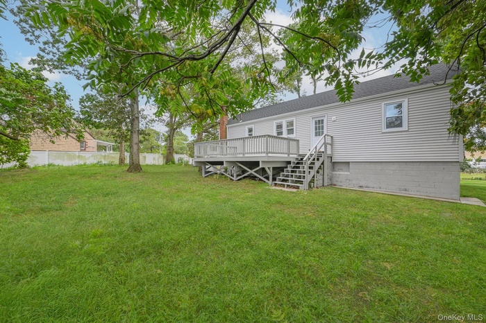 Rear view of house featuring a wooden deck and roof with shingles