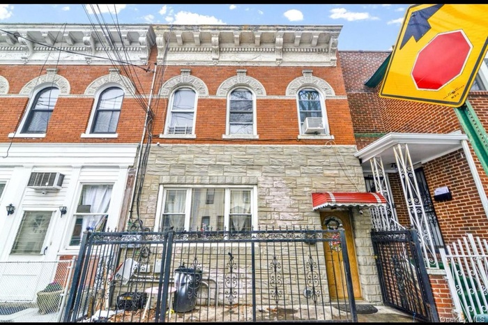 Italianate home with a fenced front yard, stone siding, brick siding, and a gate