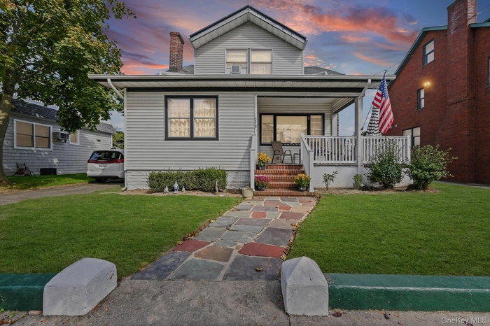 View of front facade with a porch, a front lawn, and a chimney