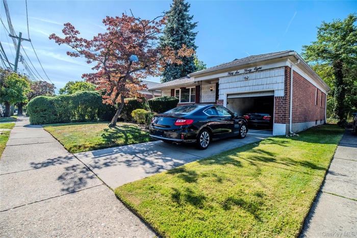 View of front of house featuring a garage, concrete driveway, brick siding, and a front yard
