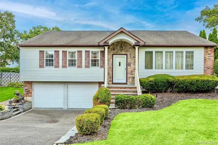 View of front of property featuring a shingled roof, driveway, a front yard, and an attached garage