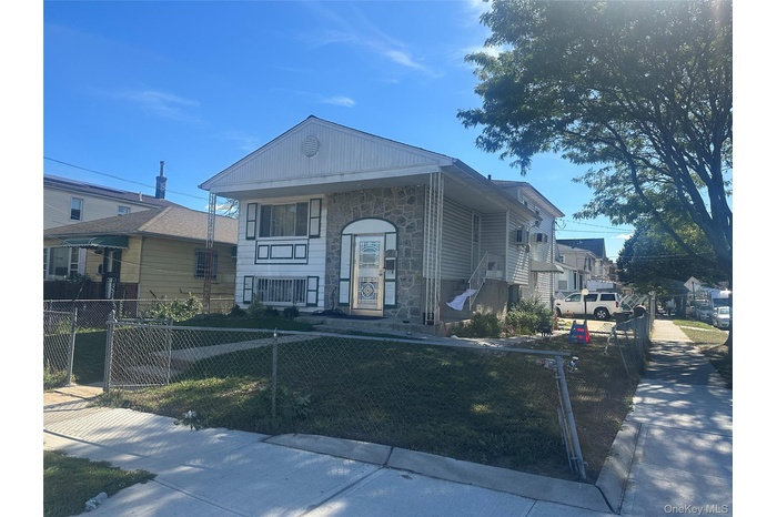 View of front of home featuring stone siding and a fenced front yard