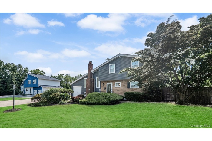 View of front of house featuring stone siding, a chimney, and an attached garage