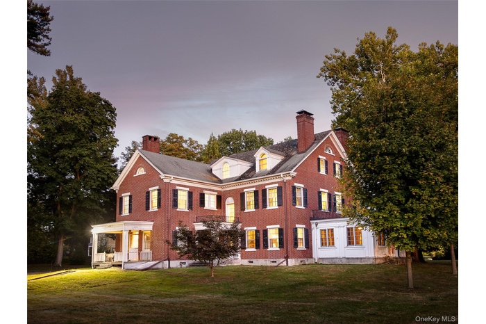 Back of property featuring a chimney, brick siding, and a lawn