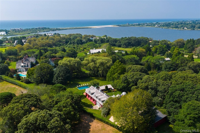 Aerial overview of property's location featuring a large body of water and a heavily wooded area