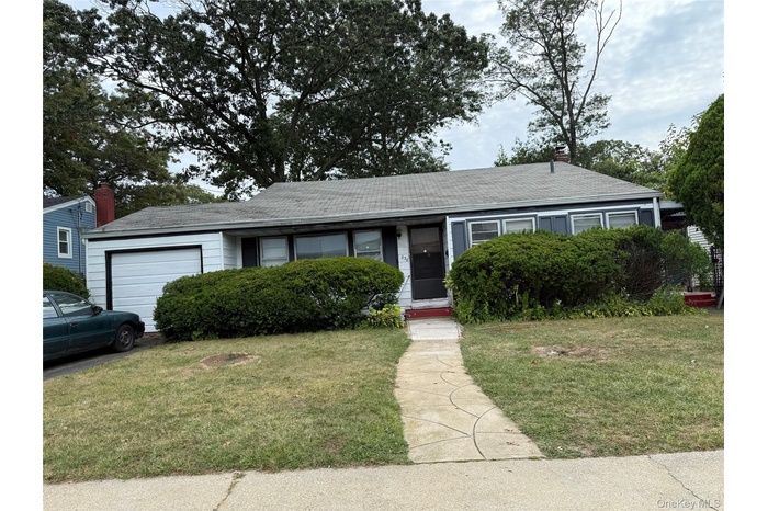 Ranch-style home featuring a front yard, an attached garage, and a shingled roof