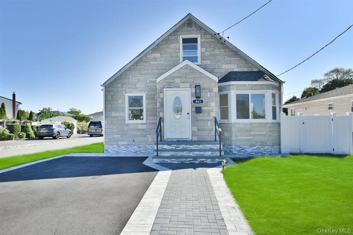 View of front of house with a front lawn and stone siding