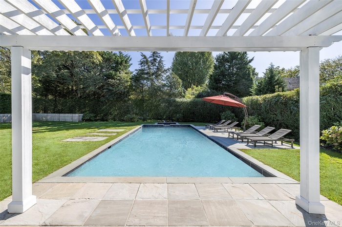View of pool featuring a patio area, a pergola, a fenced backyard, and view of wooded area