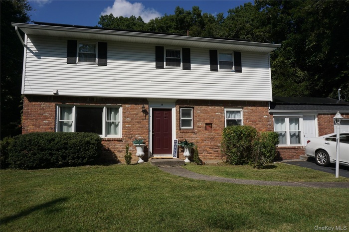 Colonial-style house with brick siding and a front lawn