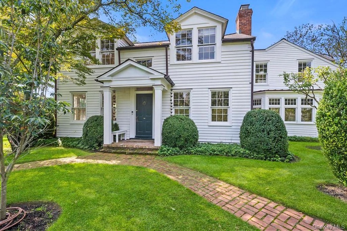View of front of property with a chimney and a front lawn