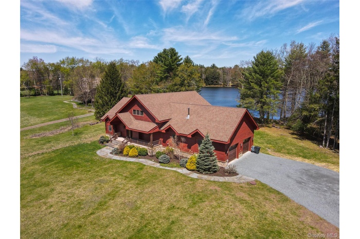 View of front of home with a front lawn, a porch, a garage, and asphalt driveway