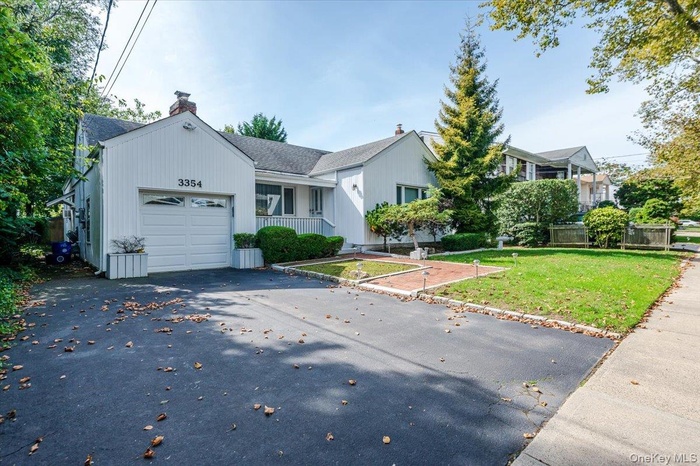 View of front of home with a chimney, a front lawn, a shingled roof, an attached garage, and asphalt driveway