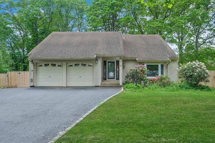 View of front of property featuring an attached garage, a shingled roof, and driveway
