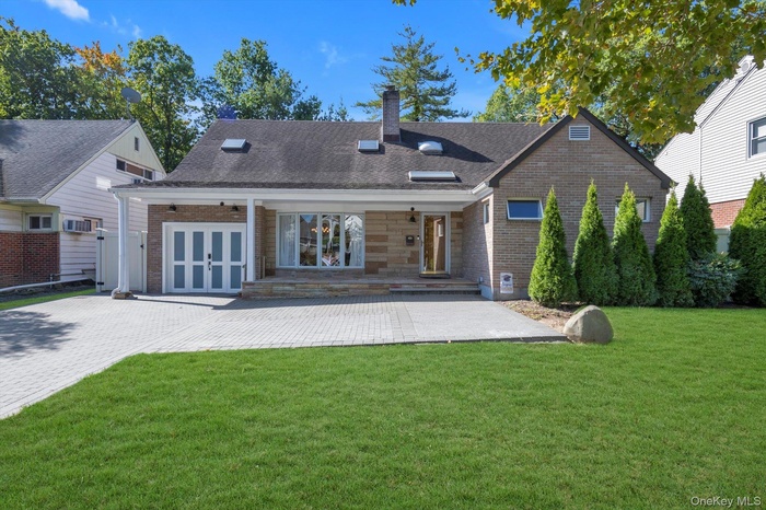 Back of property with a yard, french doors, a chimney, and brick siding