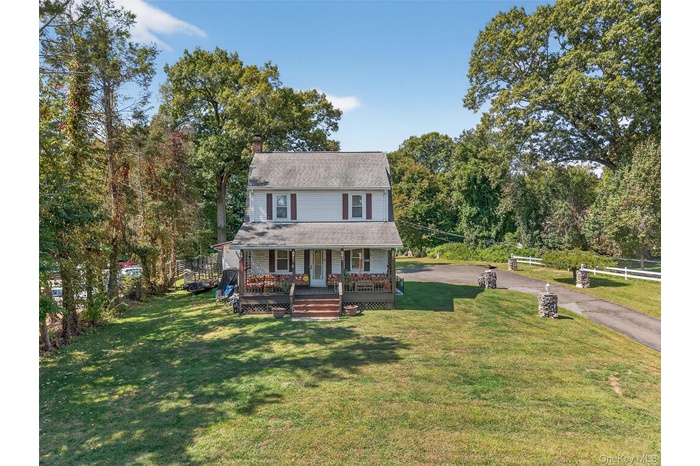 View of front of home with a porch, a front lawn, a chimney, and view of wooded area