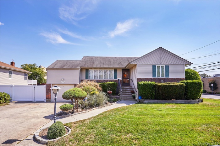 View of front of property with brick siding, driveway, and a garage