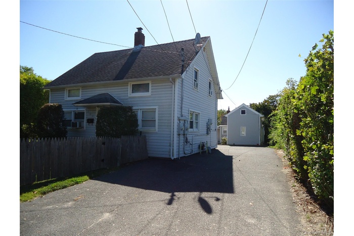 View of front of property with a chimney, driveway, and a shingled roof
