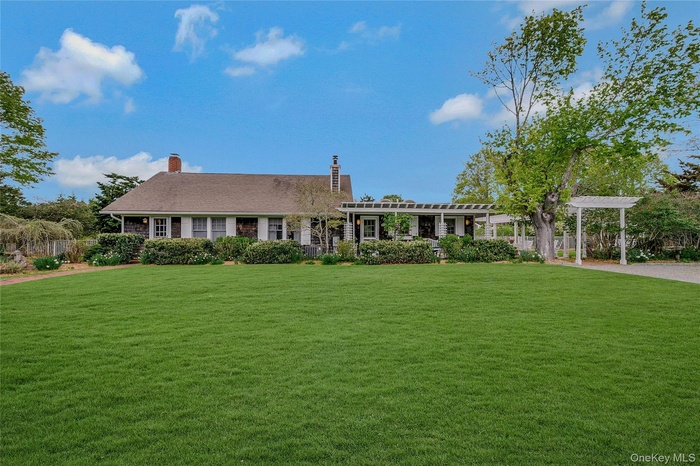 Ranch-style home featuring a pergola, a front yard, and a chimney