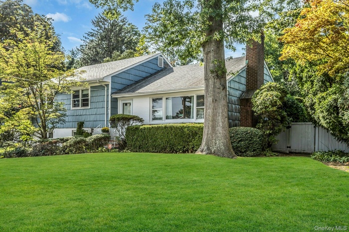 Tri-level home featuring roof with shingles and a chimney