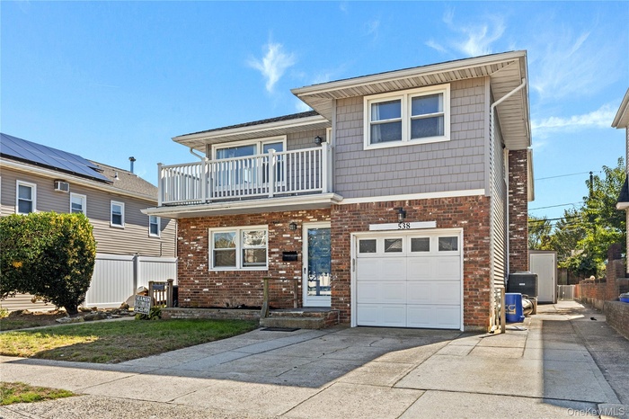 Traditional home with driveway, a balcony, brick siding, and a garage