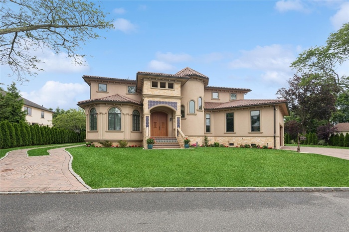 Mediterranean / spanish home with a front yard, stucco siding, stone siding, and a tiled roof