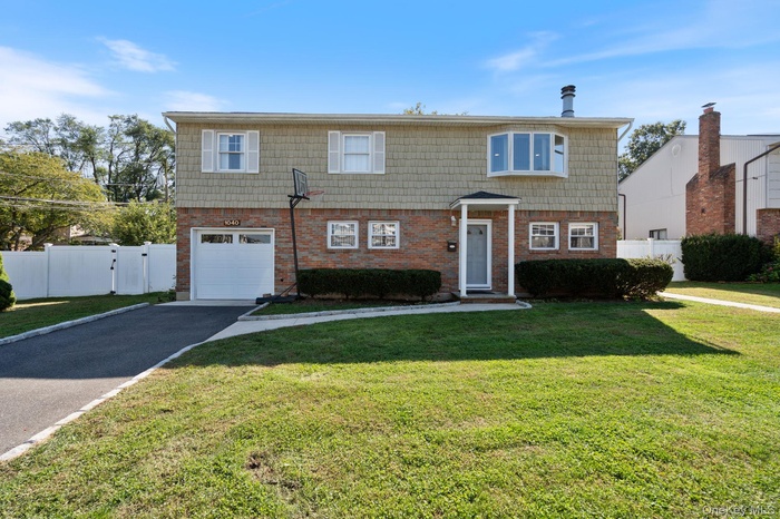 View of front of property featuring driveway, brick siding, and a garage