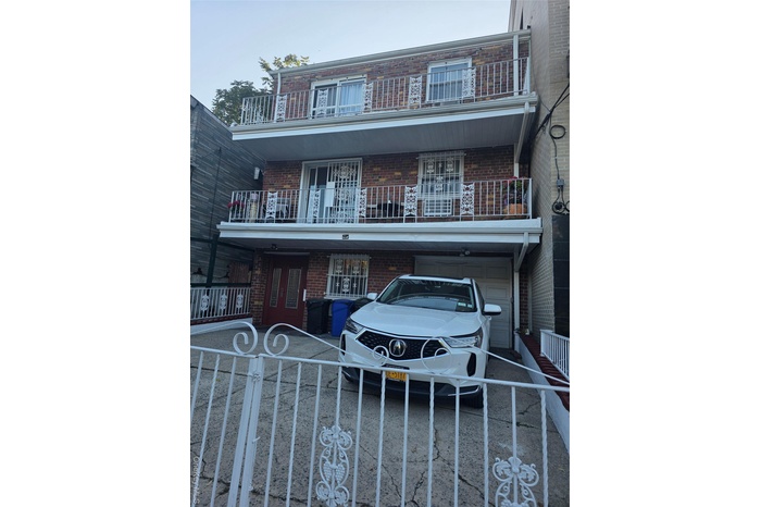 View of front of home featuring brick siding, a balcony, and a fenced front yard