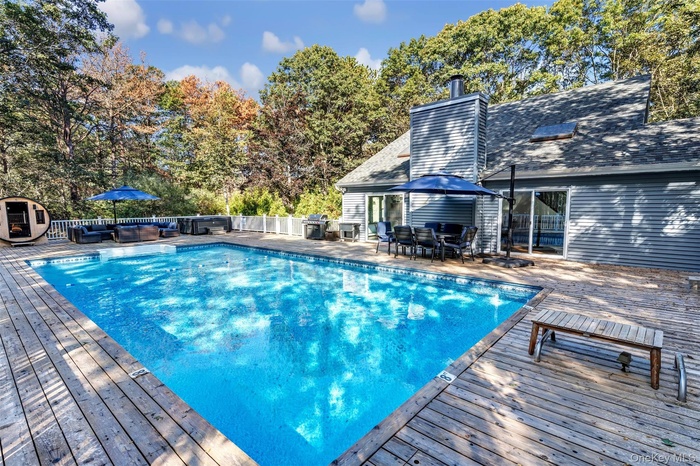 View of pool with a patio area, outdoor dining area, a wooden deck, view of wooded area, and outdoor lounge area