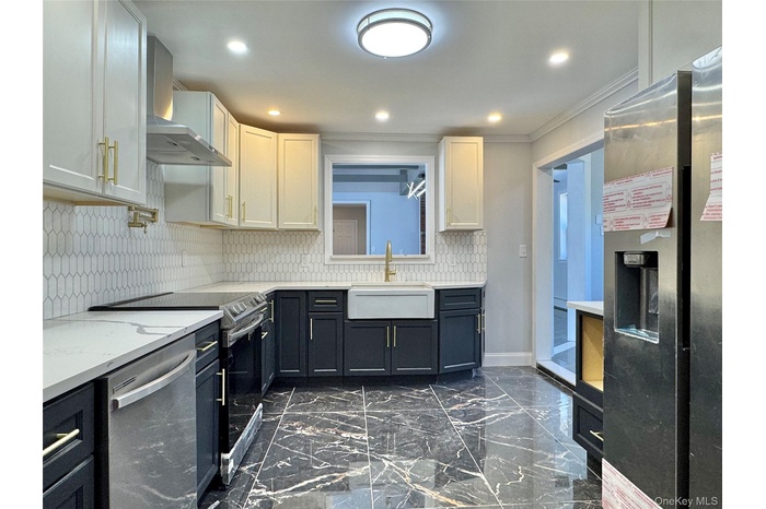 Kitchen featuring stainless steel appliances, wall chimney exhaust hood, decorative backsplash, dark cabinetry, and dark marble finish flooring