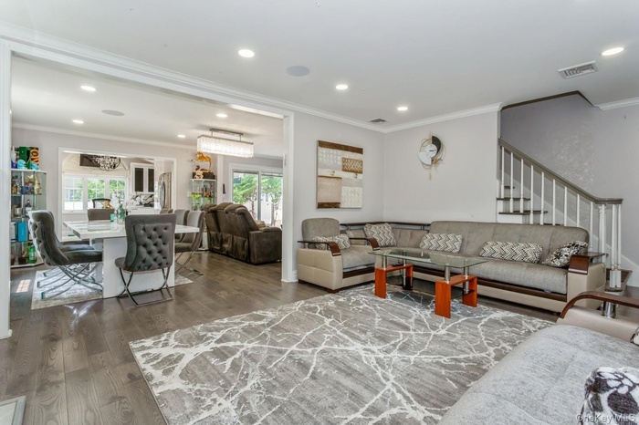 Living room with wood finished floors, plenty of natural light, recessed lighting, crown molding, and stairs