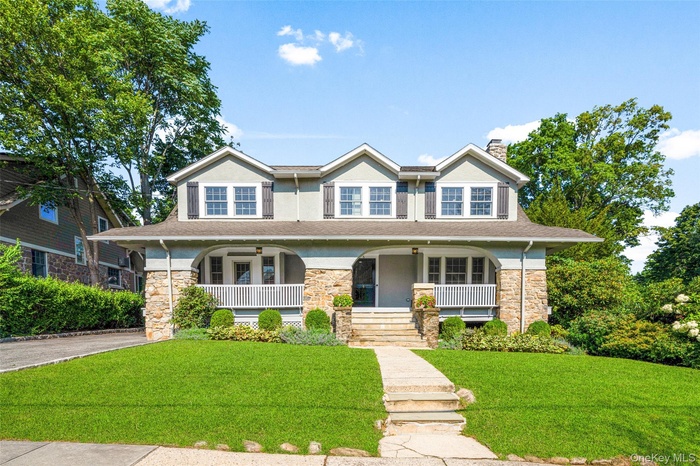 Craftsman-style house featuring covered porch, a front lawn, a chimney, and stucco siding