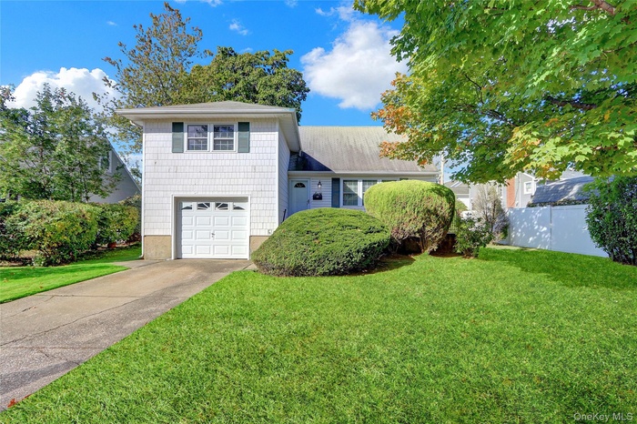 Tri-level home featuring concrete driveway and a garage