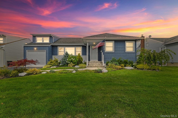 View of front facade with a yard, a garage, and roof with shingles