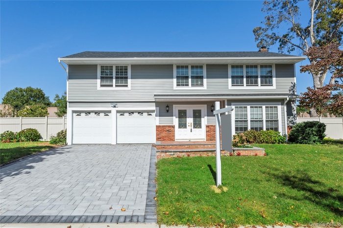 Traditional-style house featuring decorative driveway, french doors, a chimney, and an attached garage