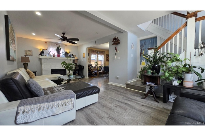 Living room featuring wood finished floors, a brick fireplace, ceiling fan, recessed lighting, and stairway