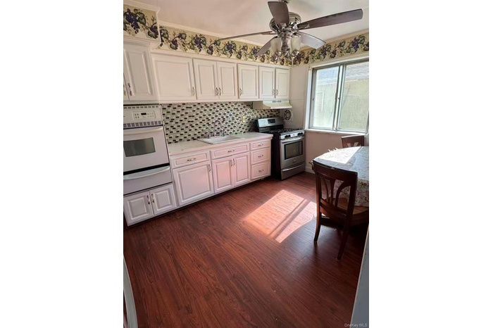 Kitchen featuring white cabinetry, dark wood-style flooring, gas range, and white oven