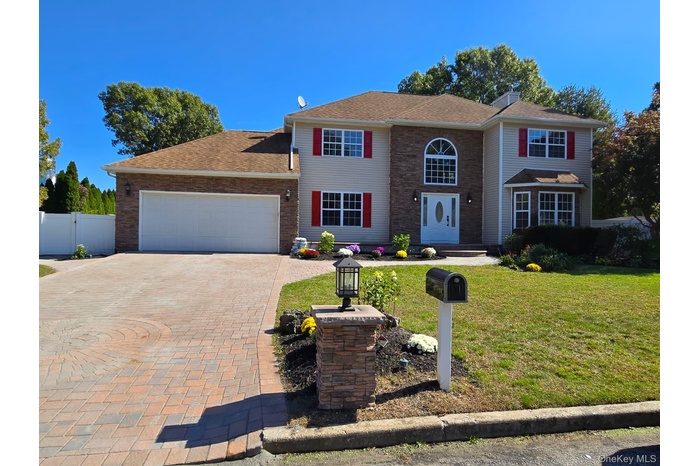 Traditional-style home featuring decorative driveway, a garage, and roof with shingles