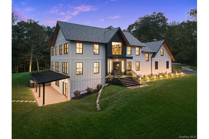 Side view of property at dusk featuring roof with shingles, a yard, and board and batten siding