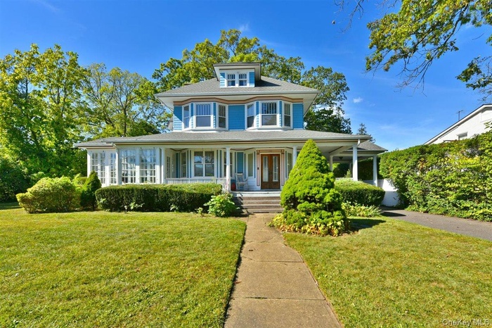 American foursquare style home featuring a front yard and covered porch