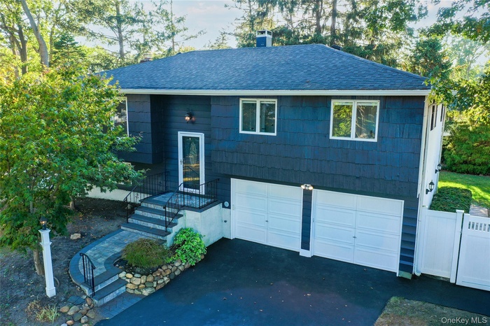 View of front of home with roof with shingles, a chimney, driveway, and an attached garage