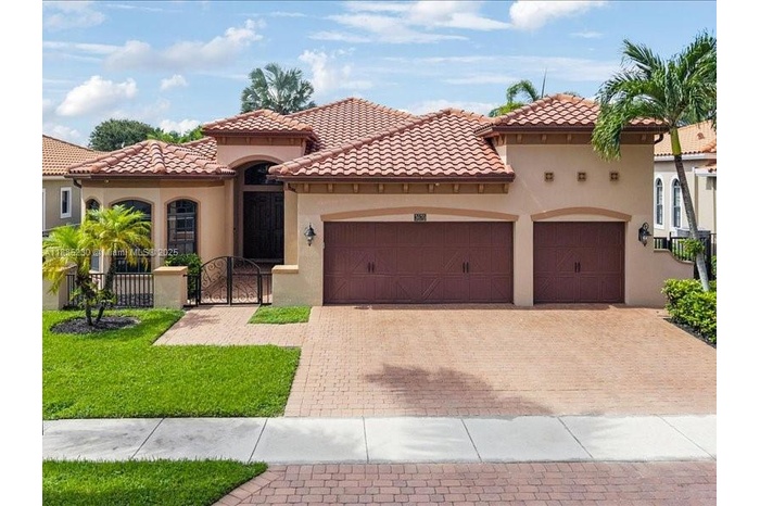 Grand façade featuring timeless architectural design, spacious three-car garage, and paver driveway.