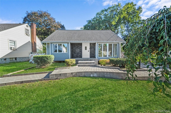 View of front of house with a front yard, roof with shingles, and a sunroom