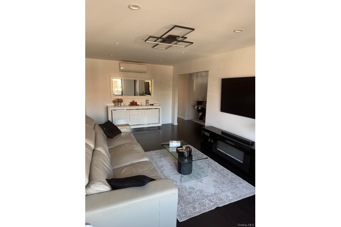 Living room featuring dark wood finished floors, recessed lighting, and a wall mounted AC