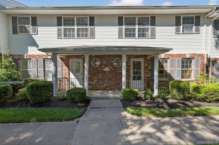 Traditional townhome featuring covered porch and brick siding