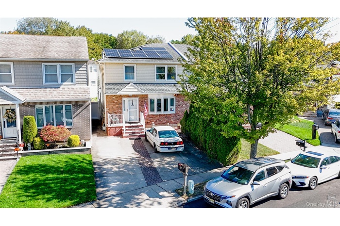Traditional home featuring brick siding, roof with shingles, and solar panels